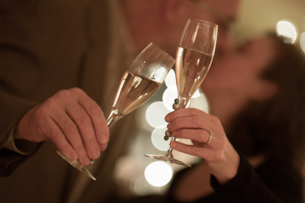 Focusing on the glasses in the foreground as our lovely couple steal a romantic moment puts them out of focus and gives the picture a feeling and air of mystery and privacy.